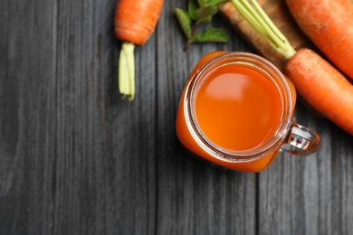 Flat lay composition with mason jar of carrot drink on wooden table, space for text