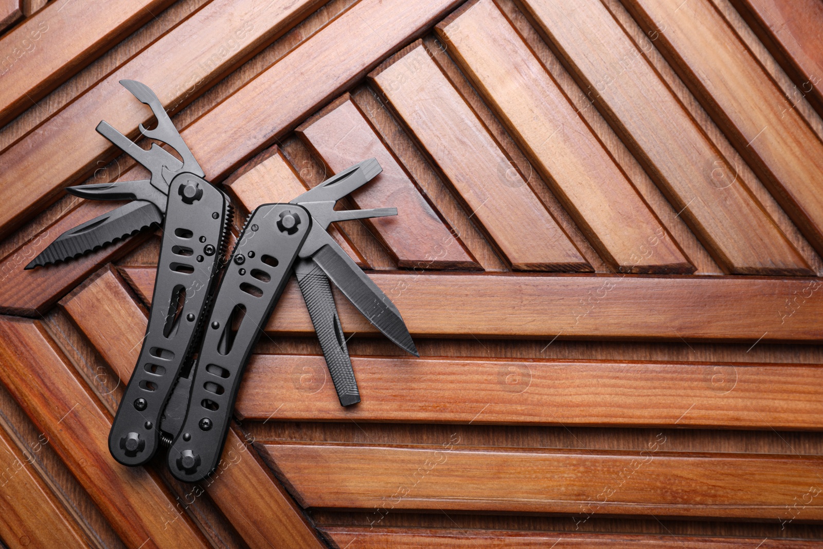 Photo of Modern compact portable multitool on wooden table, top view. Space for text