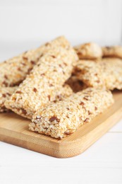 Photo of Tasty sesame seed bars on white wooden table, closeup