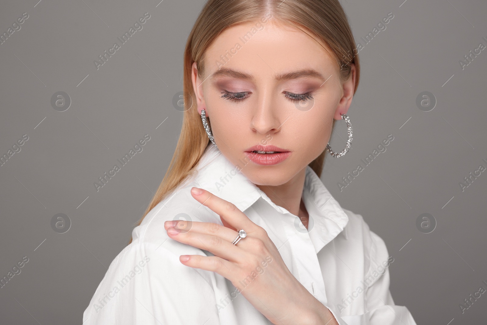 Photo of Beautiful young woman with elegant jewelry on gray background