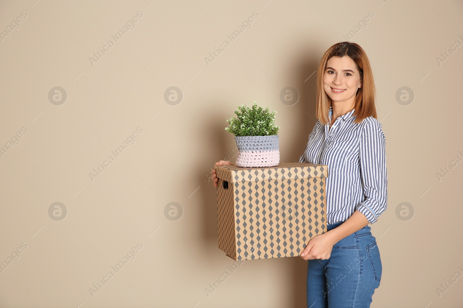 Photo of Woman with moving box and plant on color background. Space for text