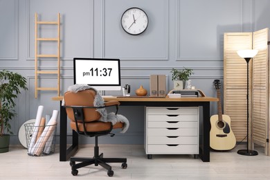 Photo of Stylish workplace with computer, houseplant and stationery on wooden desk near grey wall at home