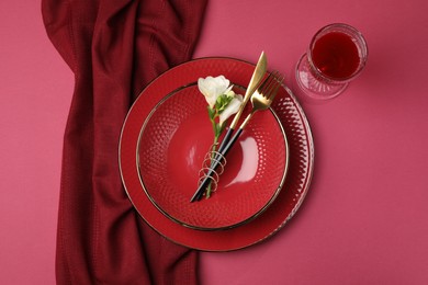 Photo of Stylish table setting with cutlery and floral decor on pink background, top view