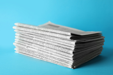Photo of Stack of newspapers on light blue background. Journalist's work