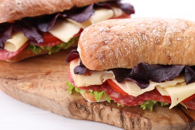 Photo of Delicious sandwiches with cheese, salami, tomato on white wooden table, closeup