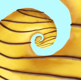 Image of Twisted donut with banana icing and chocolate topping on pale light blue background, spiral effect