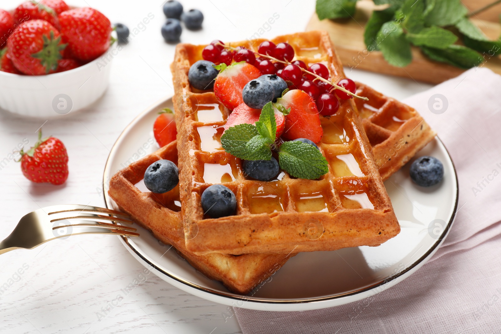 Photo of Delicious Belgian waffles with berries served on white wooden table