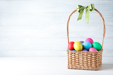 Photo of Colorful Easter eggs in wicker basket on white background. Space for text