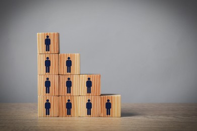 Image of Team and management concept. Wooden cubes with human icons on table against grey background, space for text