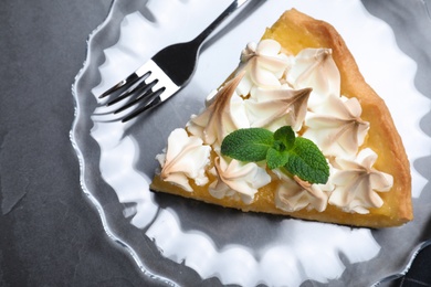 Photo of Piece of delicious lemon meringue pie with mint served on black table, top view