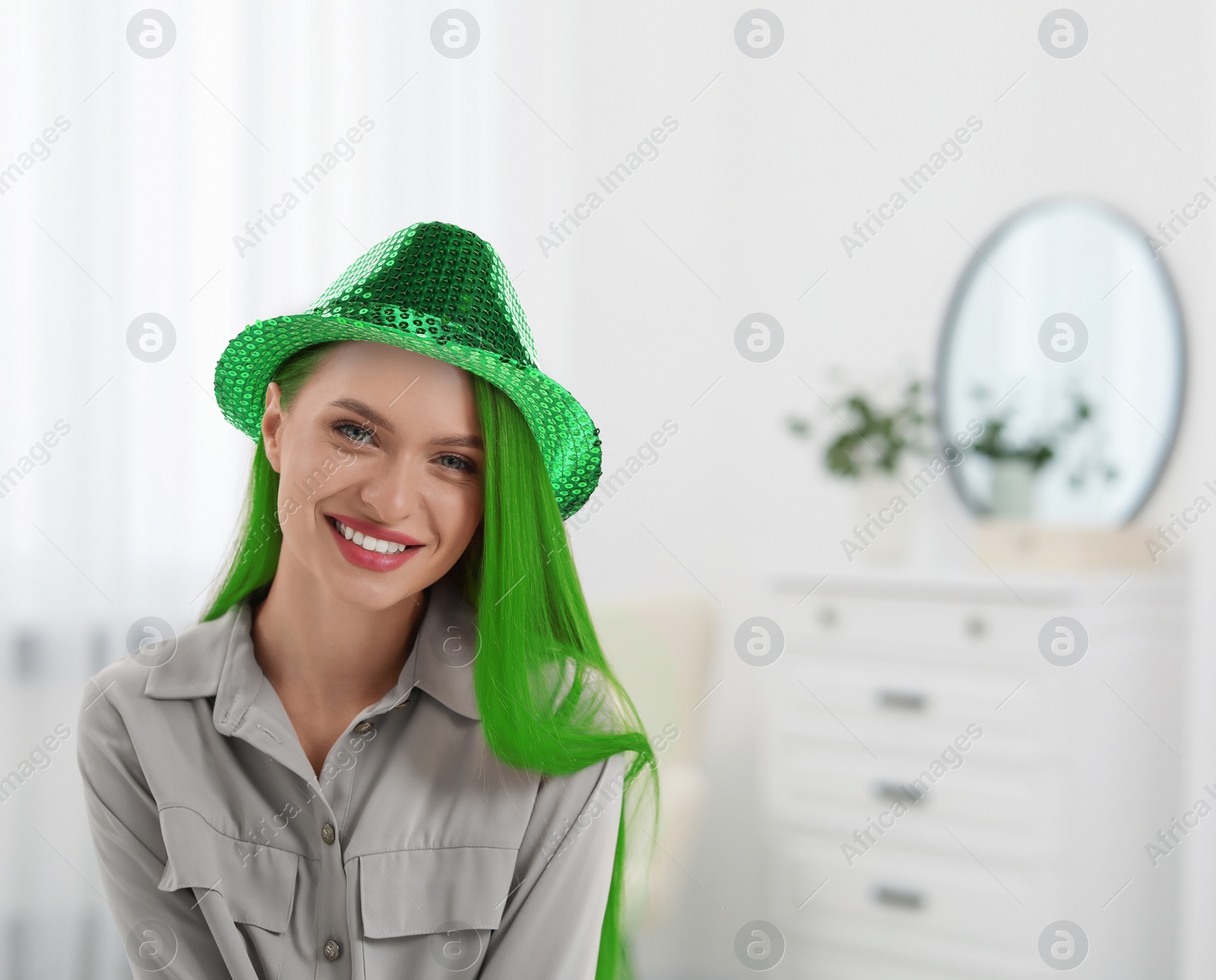 Image of St. Patrick's day party. Pretty woman with green hair and leprechaun hat indoors. Space for text