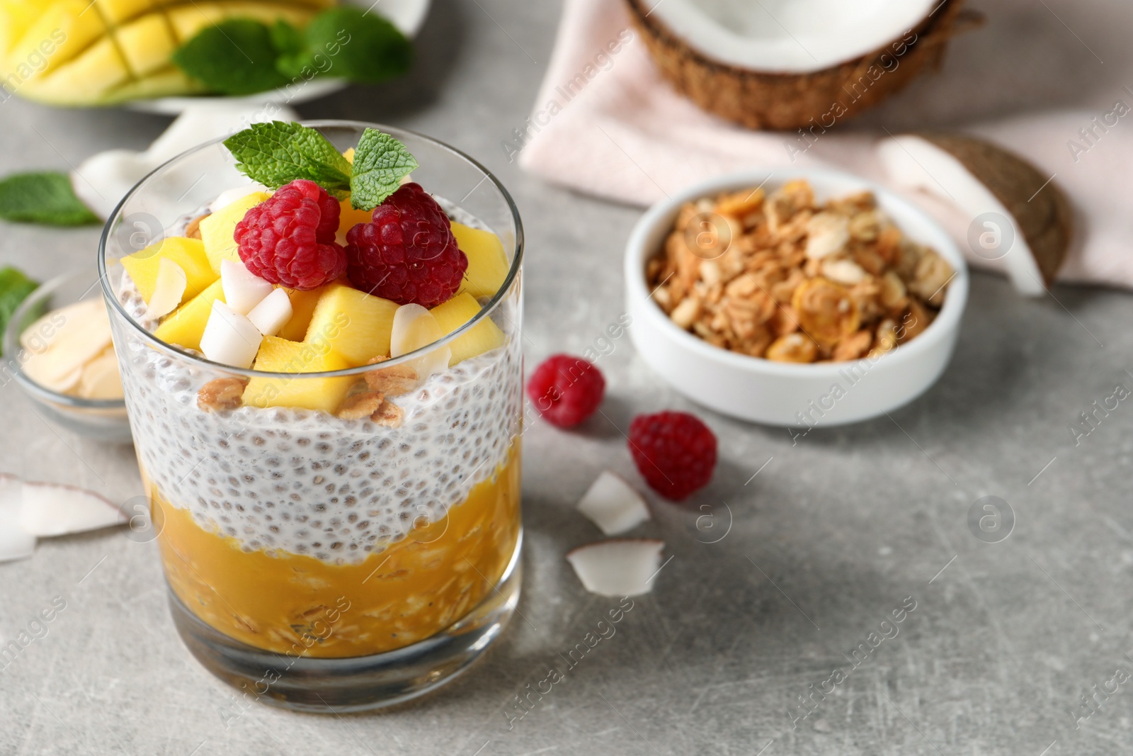 Photo of Delicious chia pudding with mango, raspberries and granola on light grey table