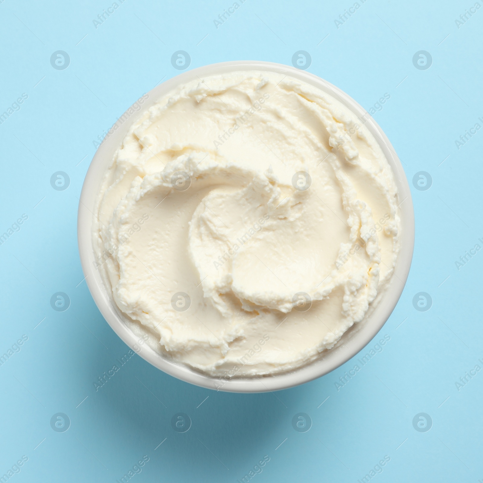 Photo of Bowl of tasty cream cheese on color background, top view