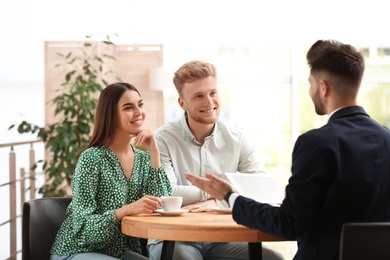 Photo of Insurance agent working with young couple in office