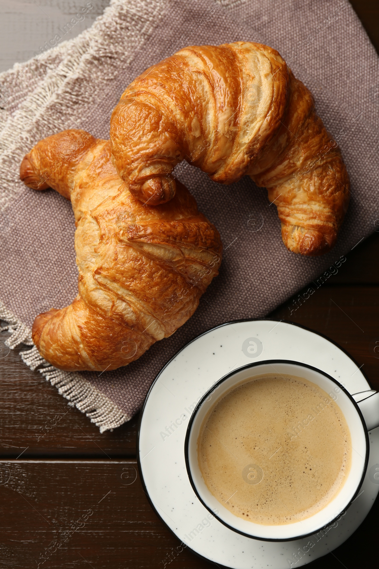 Photo of Delicious fresh croissants and cup of coffee on table, flat lay