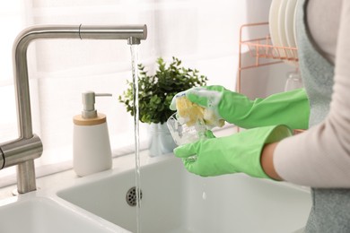 Photo of Woman washing glass at sink in kitchen, closeup