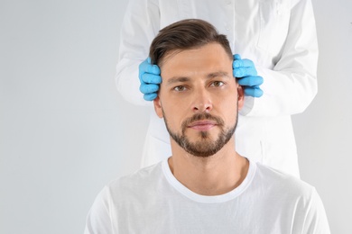 Photo of Doctor examining mature man face before cosmetic surgery on white background