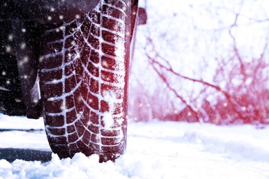 Image of Car with winter tires on snowy road, closeup view. Space for text