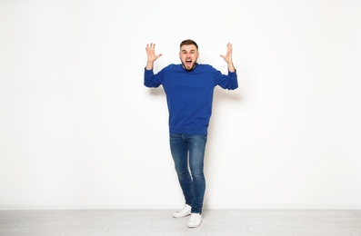 Photo of Full length portrait of emotional man against white wall