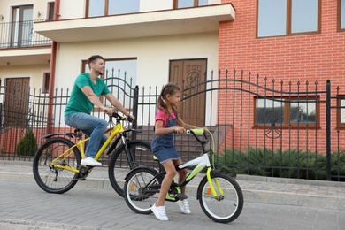 Happy father with daughter riding bicycles in city