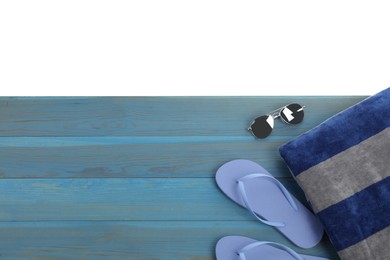 Light blue wooden surface with beach towel, flip flops and sunglasses on white background, top view. Space for text
