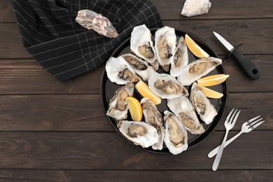 Fresh oysters with cut juicy lemon and space for text on table, flat lay