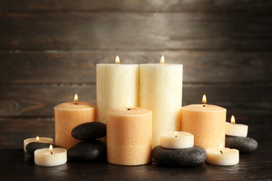 Beautiful composition with lit candles and spa stones on table