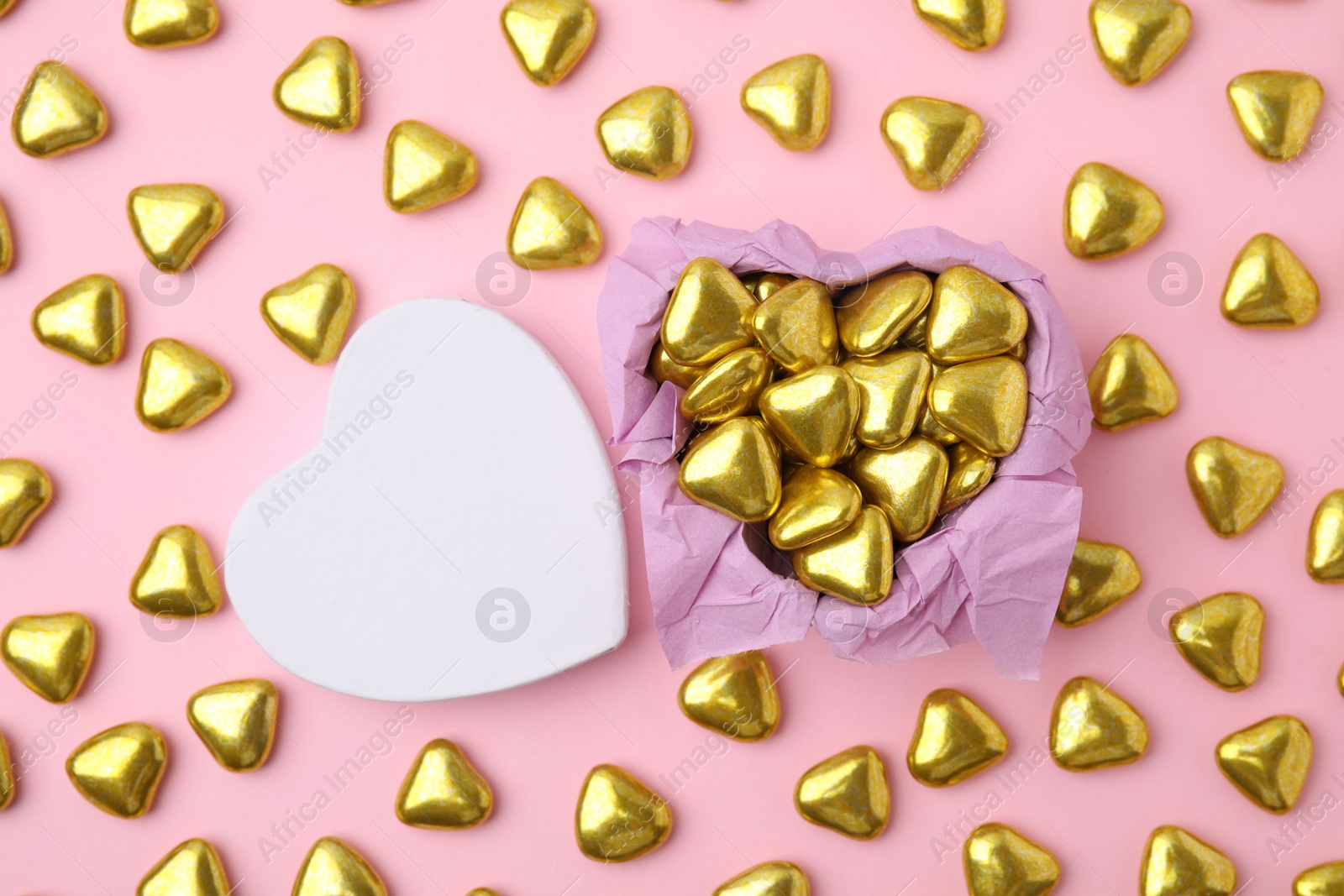 Photo of Box and delicious heart shaped candies on pink background, flat lay