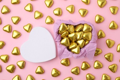 Box and delicious heart shaped candies on pink background, flat lay