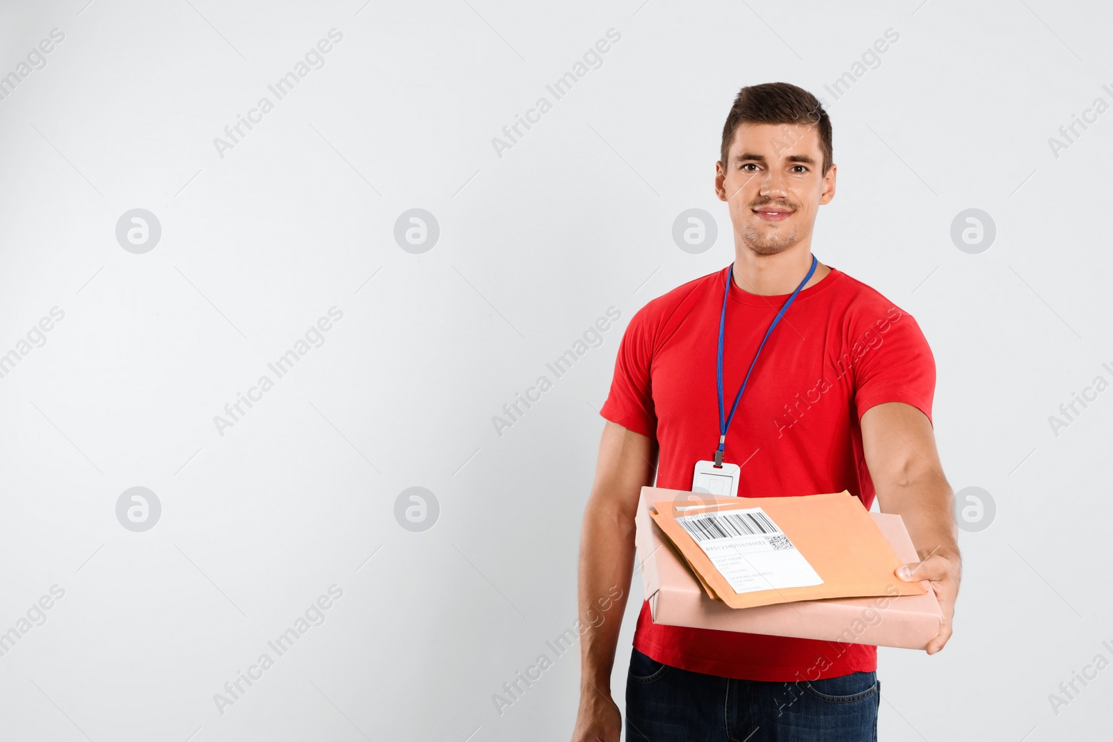 Photo of Happy young courier with parcel and envelopes on white background. Space for text