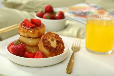 Photo of Cottage cheese pancakes with strawberries and honey served on white bed tray