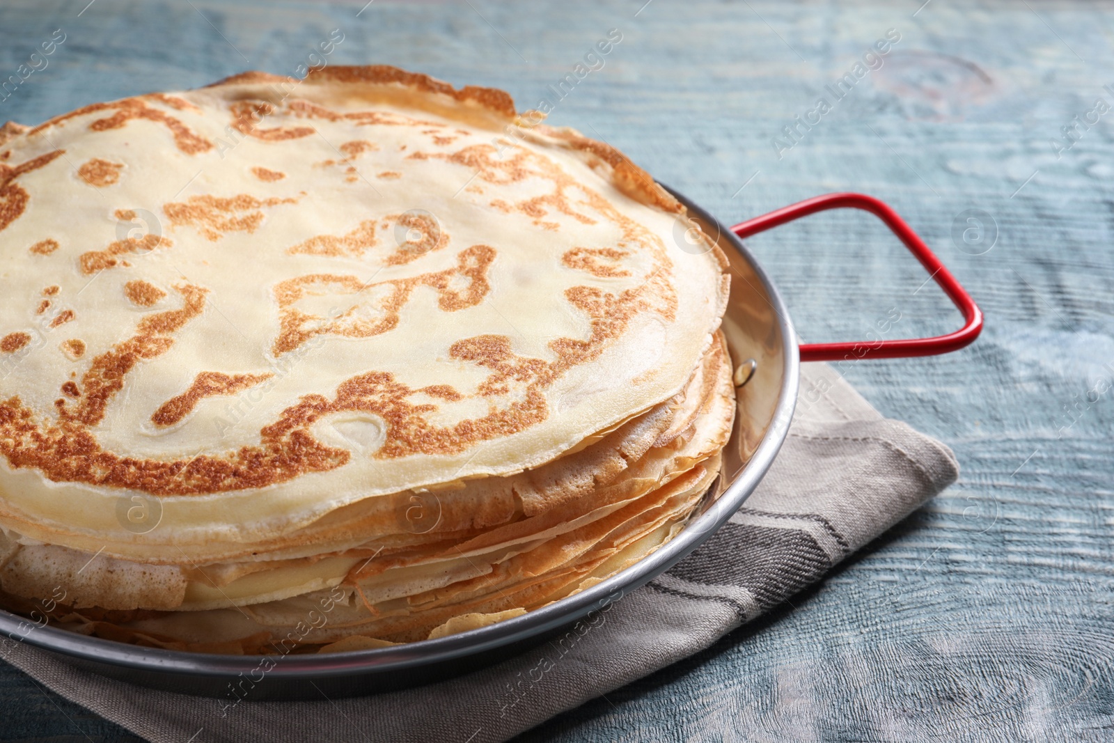 Photo of Dish with thin pancakes on wooden table