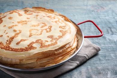 Dish with thin pancakes on wooden table