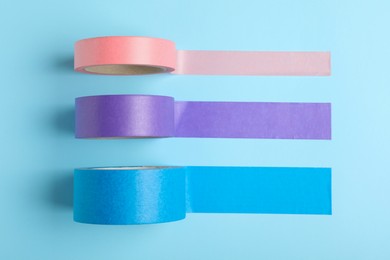 Photo of Many rolls of adhesive tape on light blue background, flat lay