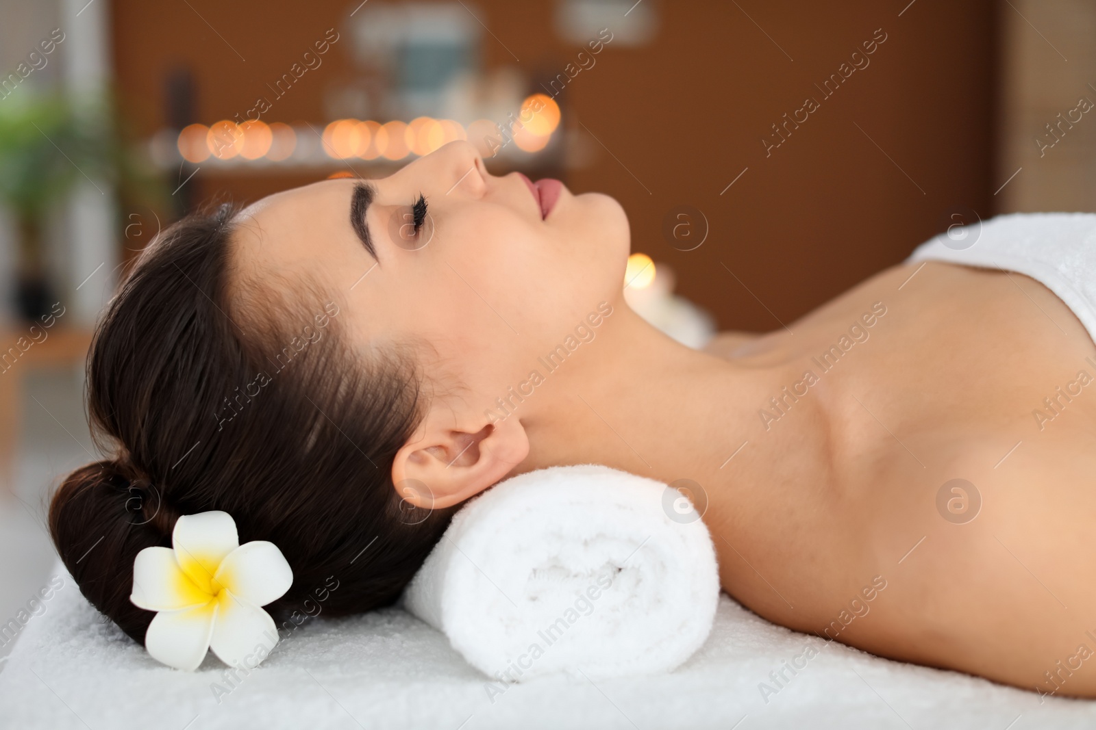 Photo of Young woman lying on massage table in spa salon