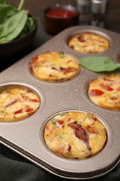 Photo of Freshly baked bacon and egg muffins with cheese in tin on table, closeup