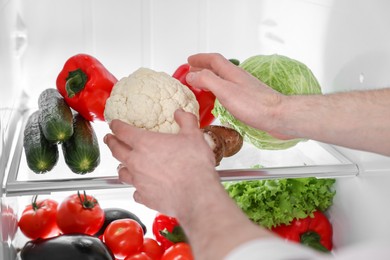 Photo of Man taking cauliflower out of refrigerator, closeup