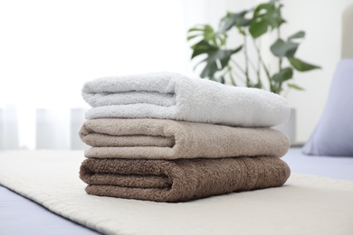 Stack of clean towels on bed indoors