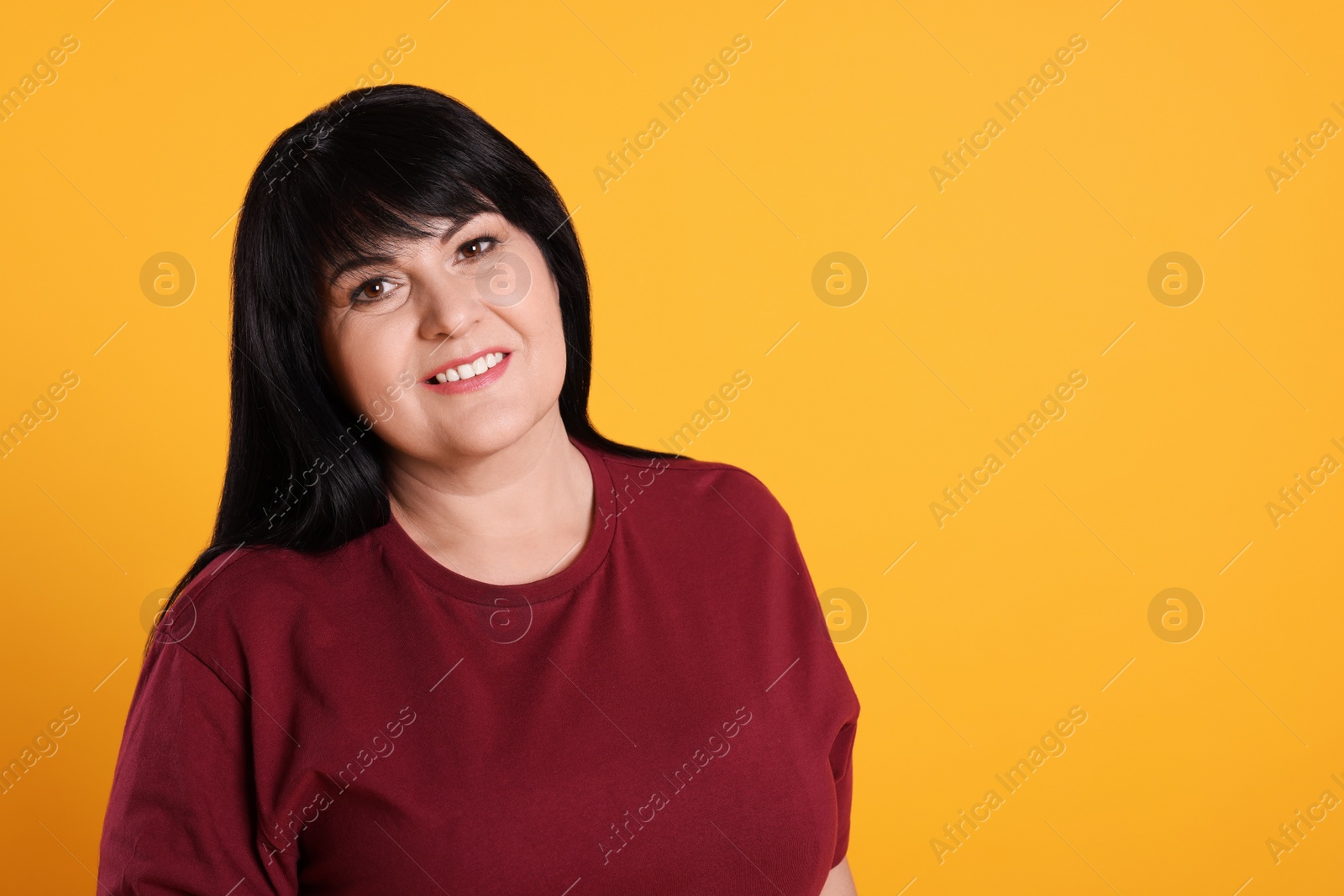 Photo of Beautiful overweight mature woman with charming smile on yellow background. Space for text