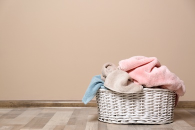 Photo of Laundry basket with dirty clothes on floor indoors. Space for text