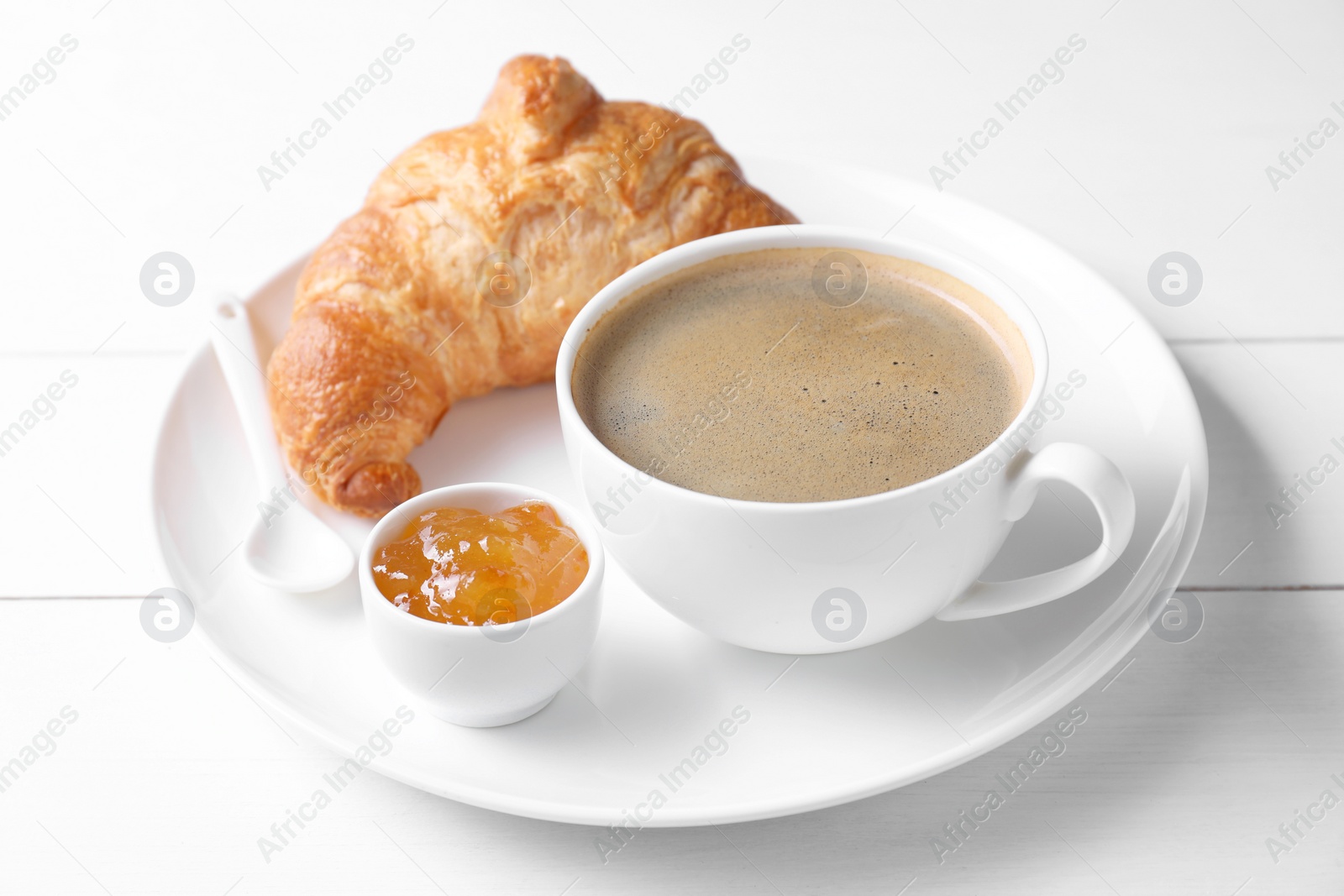 Photo of Fresh croissant, jam and coffee on white wooden table. Tasty breakfast