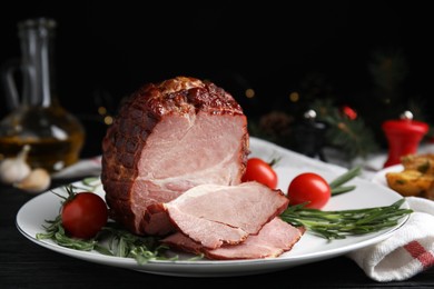 Photo of Plate with delicious ham, tomatoes and rosemary on black wooden table