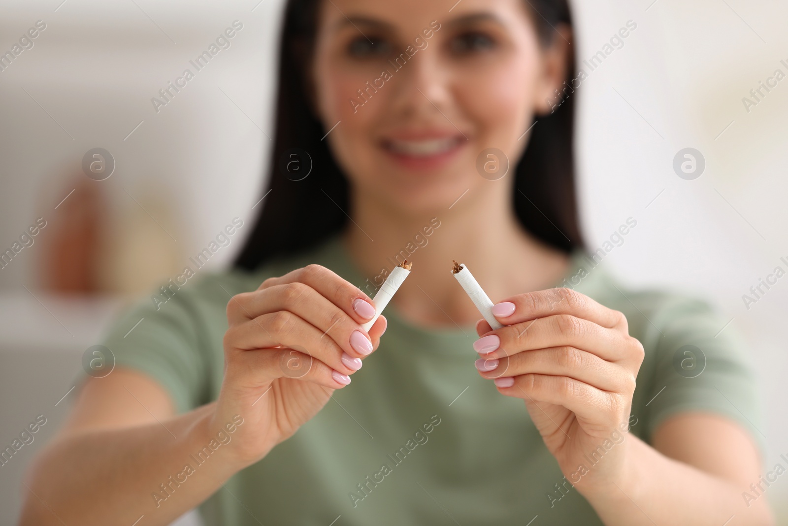 Photo of Stop smoking concept. Woman holding pieces of broken cigarette on blurred background, selective focus