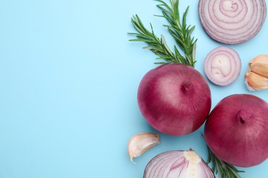 Fresh red onions, garlic and rosemary on light blue background, flat lay. Space for text