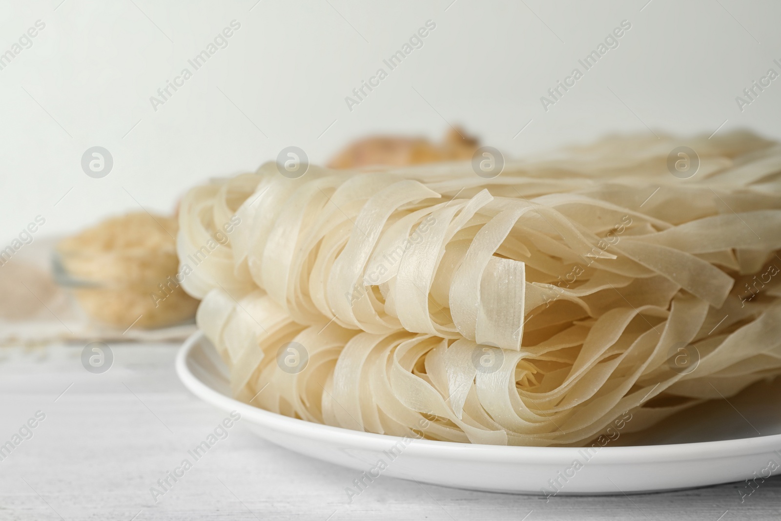 Photo of Raw rice noodles on white wooden table, closeup