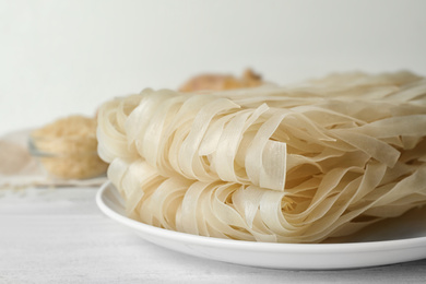 Photo of Raw rice noodles on white wooden table, closeup