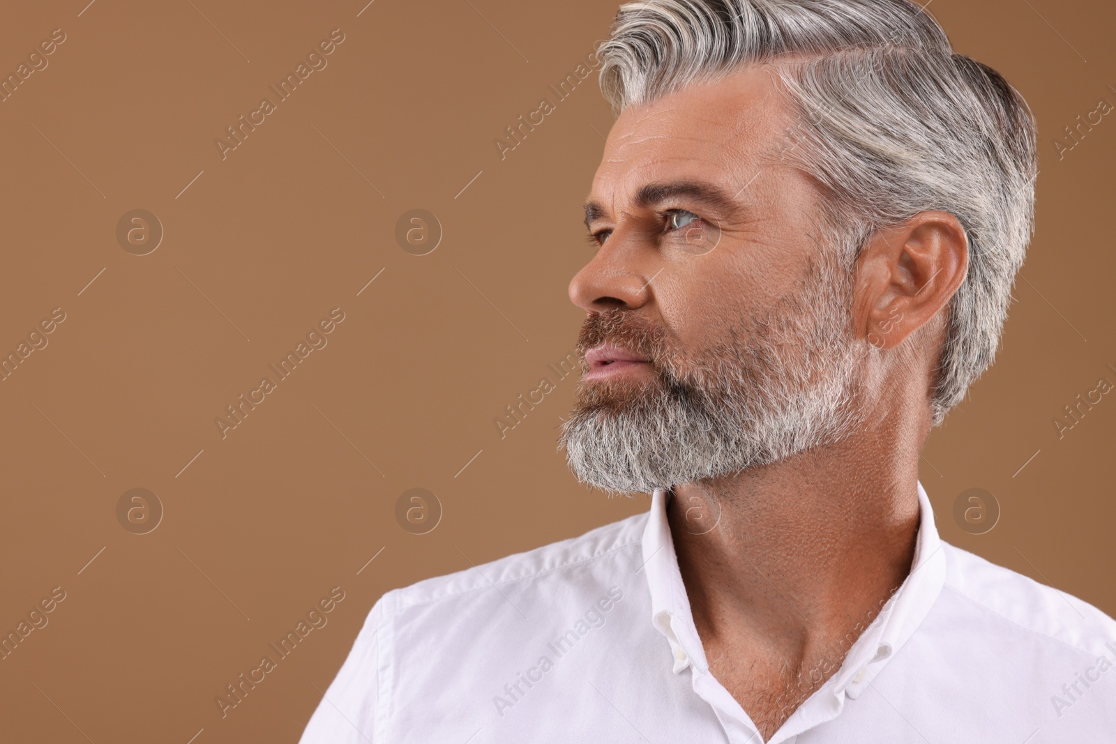 Photo of Portrait of confident man with beautiful hairstyle on light brown background. Space for text