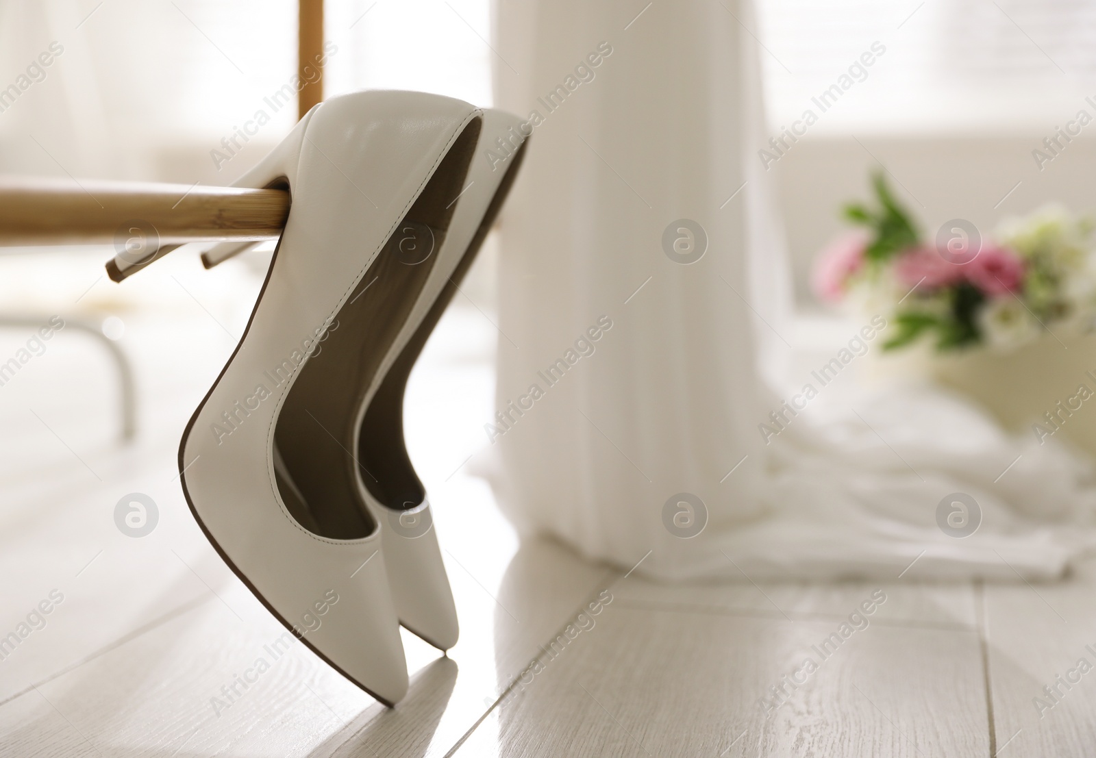 Photo of Pair of white high heel shoes and blurred wedding dress on background, space for text