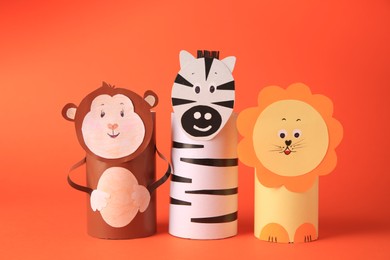 Photo of Toy monkey, lion and zebra made from toilet paper hubs on orange background. Children's handmade ideas