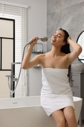 Photo of Happy woman singing after shower on tub in bathroom